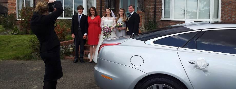 family pose with a jaguar xjl wedding car